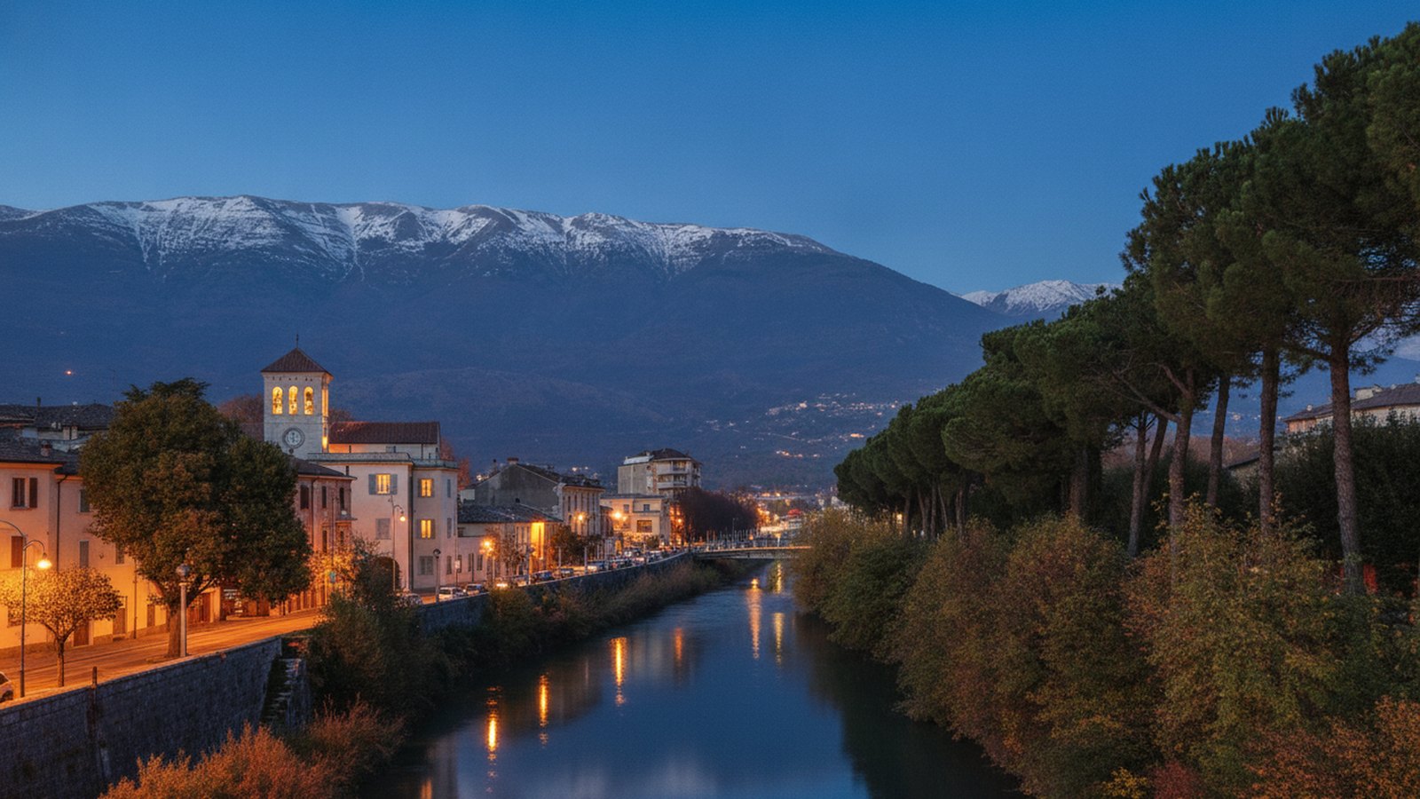 Il fiume Liri al tramonto con le montagne innevate sullo sfondo e le luci della città
